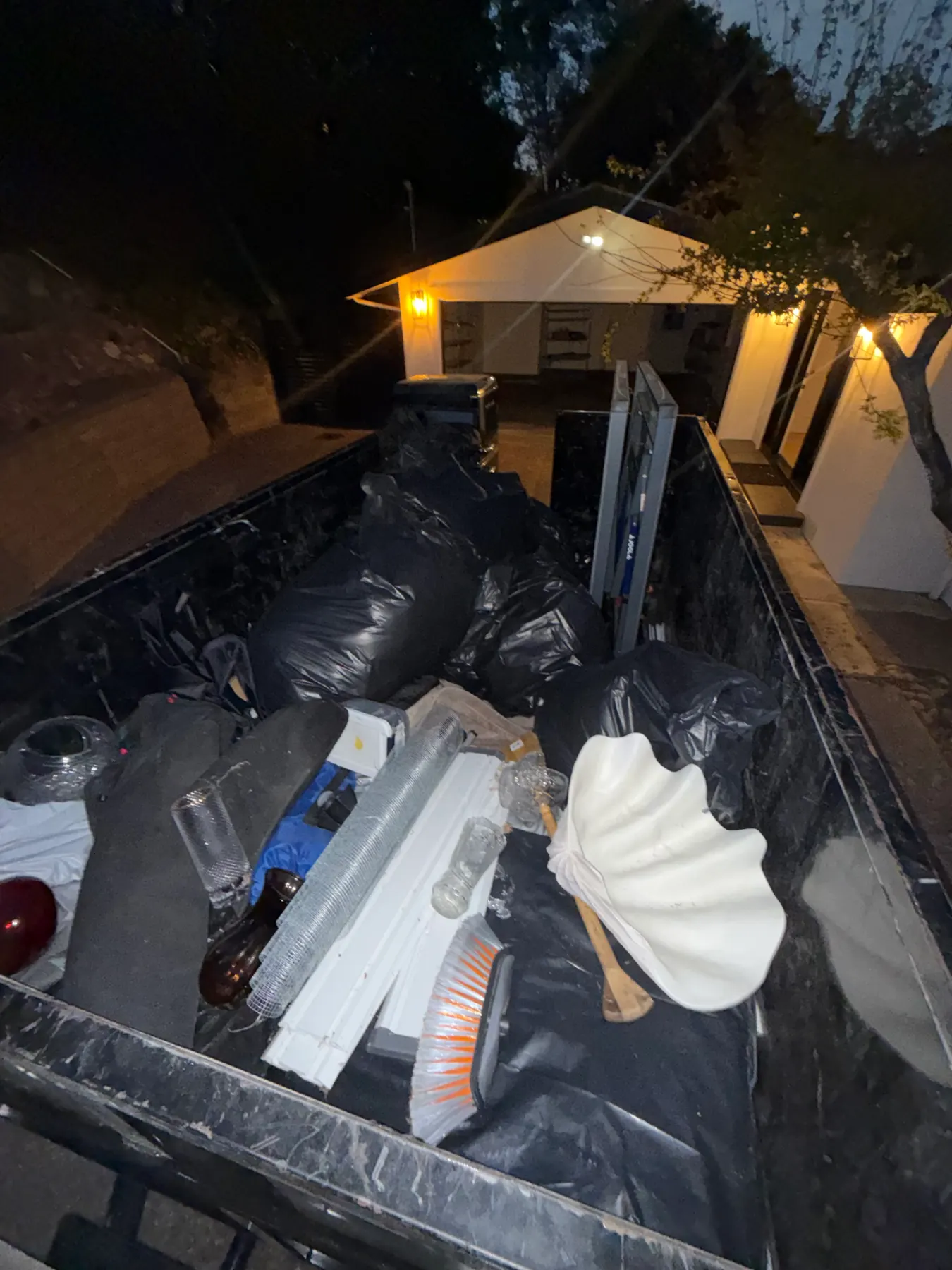 Trailer loaded with bagged junk, old fixtures and household items at an evening pickup