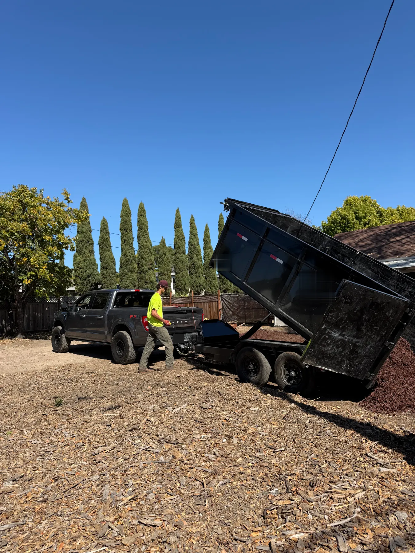 Crew member tipping the dump trailer to unload at a job site