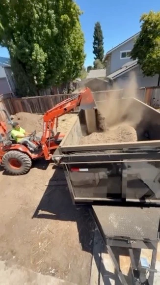 Mini excavator loading dirt into the dump trailer